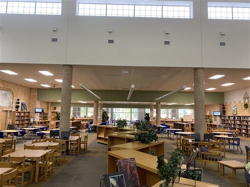 The space in the Media Center as you walk in, you see tables and chairs, and a bookshelf down the middle. 